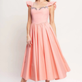 A woman wearing a light pink midi dress with ruffled cap sleeves, a fitted bodice, and a full skirt. The bodice features a decorative floral embroidered band across the neckline.