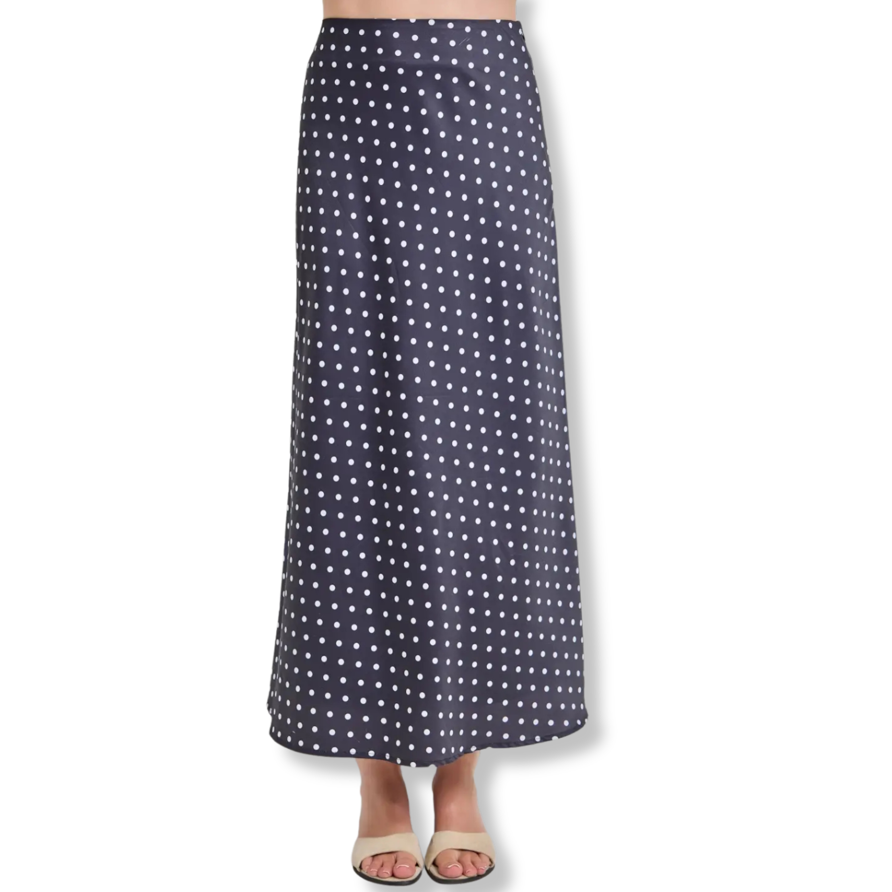 A navy blue maxi skirt with a white polka dot pattern, shown on a model from the waist down wearing beige slide sandals against a white background.