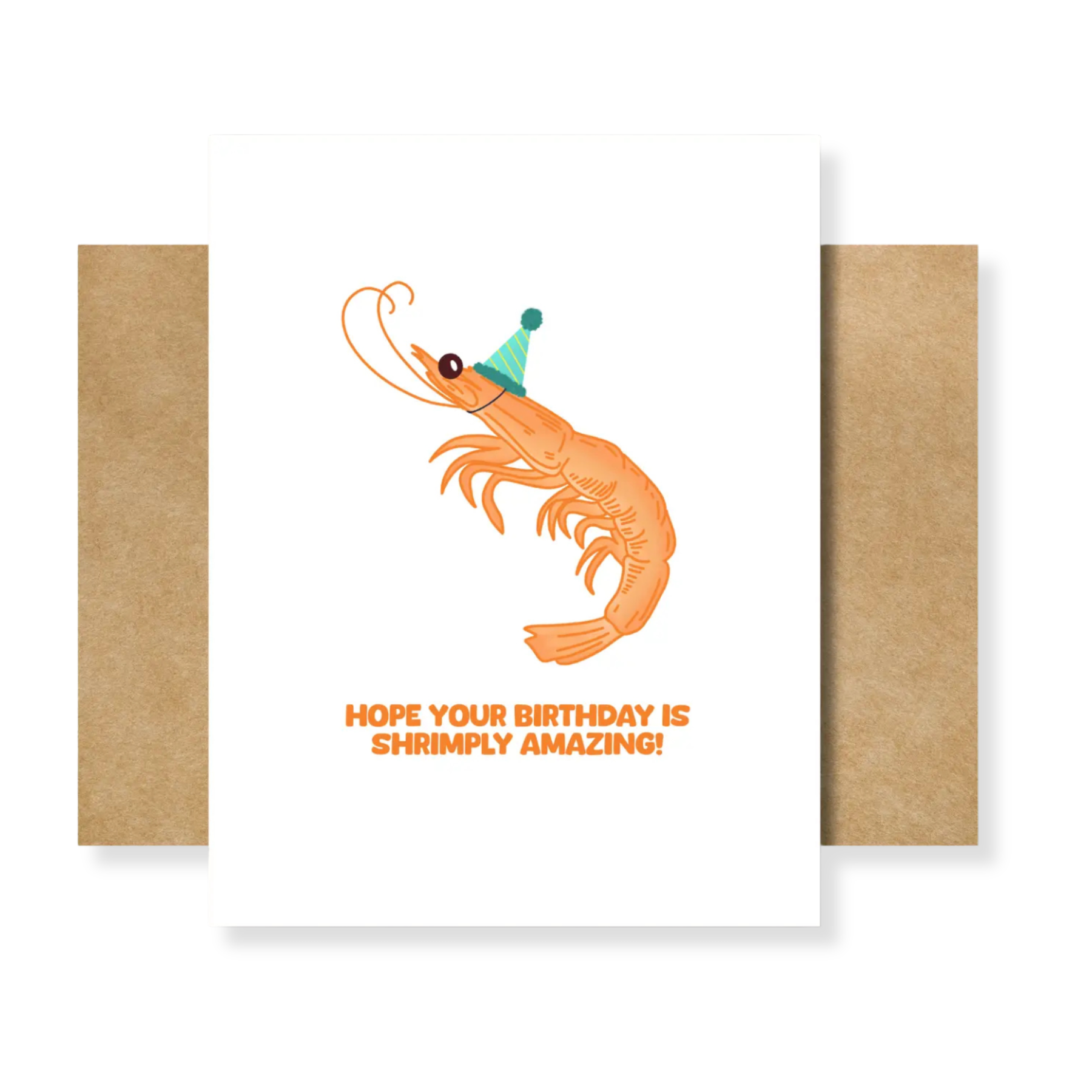 A white greeting card with a cartoon shrimp wearing a green party hat and the text 'HOPE YOUR BIRTHDAY IS SHRIMPLY AMAZING!' in orange, shown with a kraft paper envelope behind it on a white background.