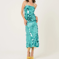 A woman modeling a turquoise sequined spaghetti-strap midi dress with yellow high-heeled sandals against a plain white studio background. Olivia Dean