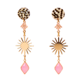 A pair of gold-tone statement dangle earrings on a solid white background. Each earring features a round top stud with a black and gold mosaic pattern, a small rose gold tassel, a gold sunburst charm, and a dangling faceted pink gemstone.