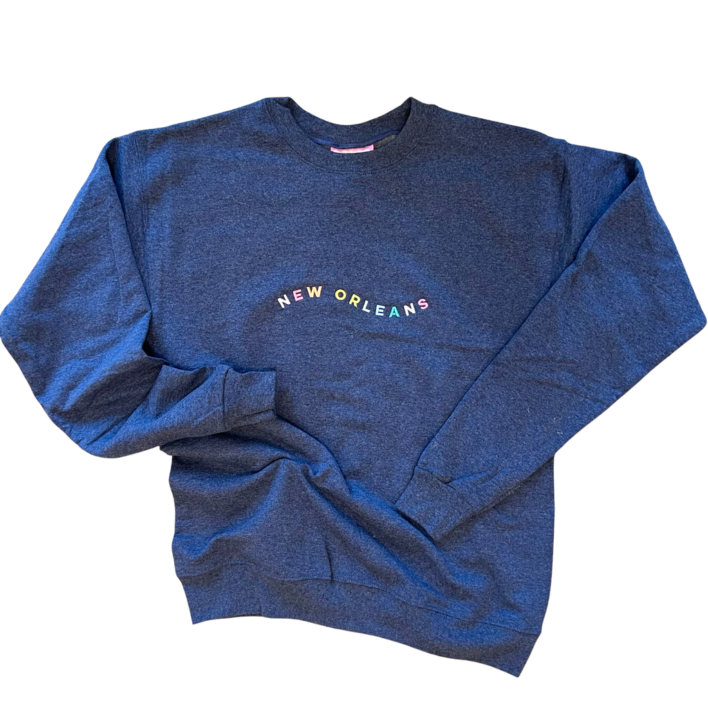 A heathered blue crewneck sweatshirt with 'NEW ORLEANS' printed in multicolored letters across the chest, laid flat on a white background.