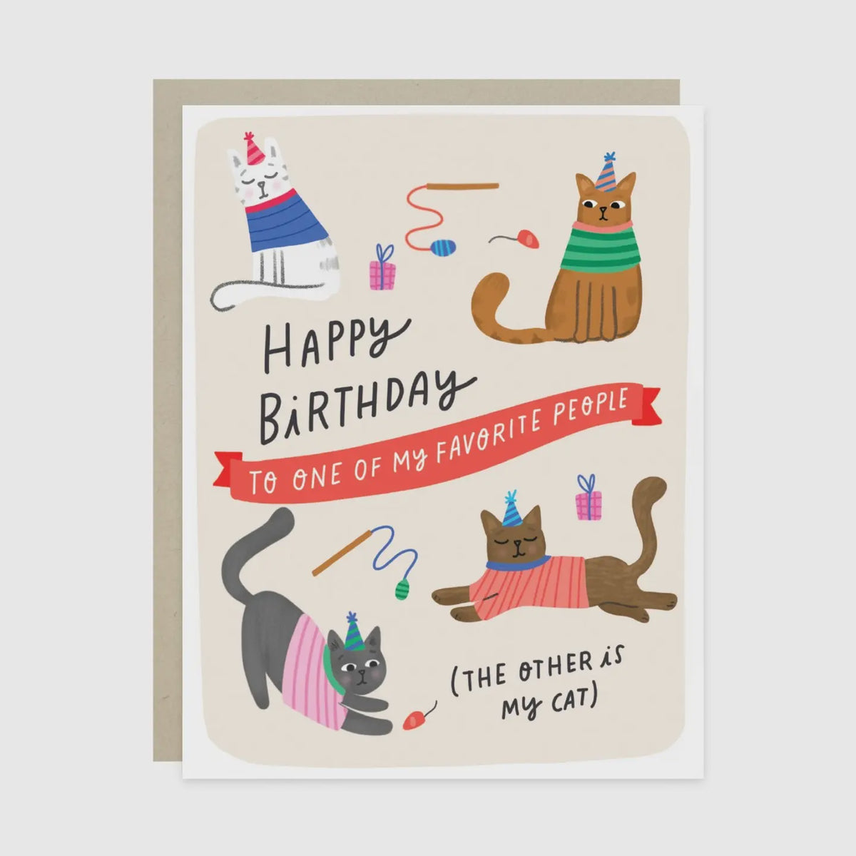 A birthday greeting card with a beige background and illustrated cats wearing party hats and colorful sweaters, with the text 'Happy Birthday to one of my favorite people (the other is my cat)'. A brown envelope is partially visible behind the card.
