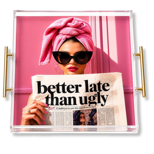 Clear acrylic serving tray with gold side handles, displaying a pink-themed art print of a woman in sunglasses with a pink towel wrap holding a newspaper that reads 'better late than ugly'.