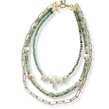 A multi-strand necklace featuring light green beads, white baroque pearls, raw shell fragments, and gold-tone chain and link details, displayed on a clean white background.