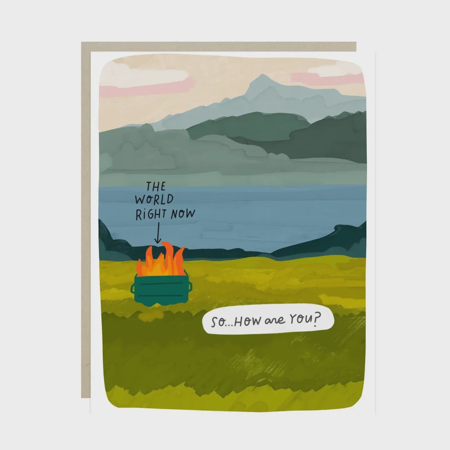 A square greeting card with a humorous landscape illustration. The scene shows a campfire burning in a grassy field with mountains and water in the background.