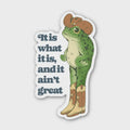 Sticker with a frog wearing cowboy boots and a hat, with text 'It is what it is, and it ain't great'.